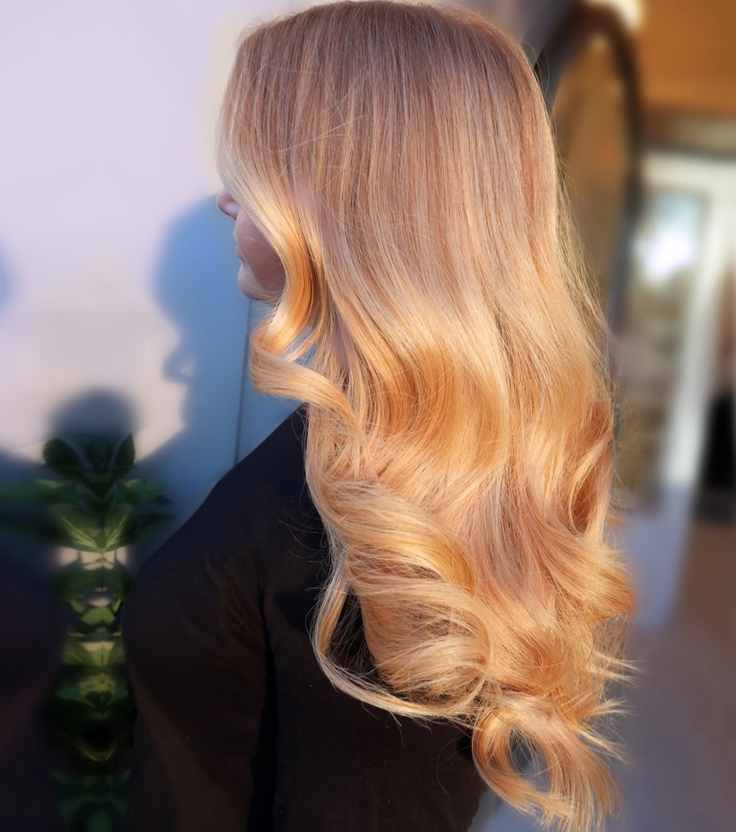 Blont hår stylat i mjuka vågor av en frisör på Peach Stockholm